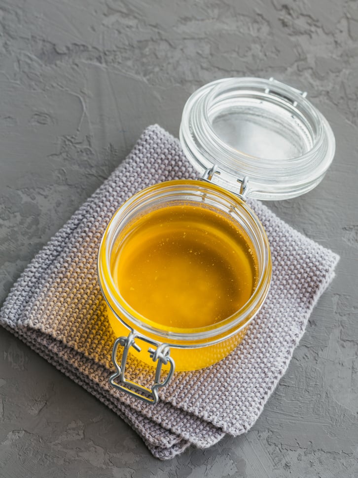 Healthy homemade Ghee or clarified butter in a jar on grey concr